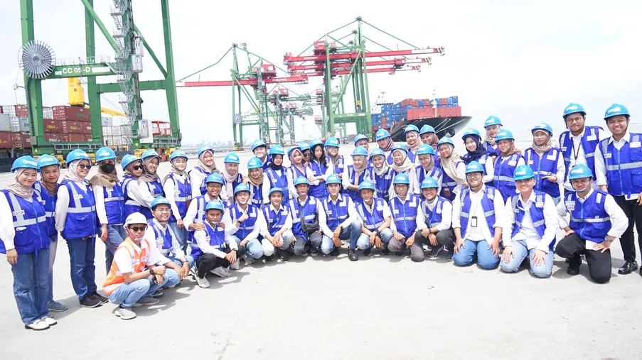 The internship group kneeling together in front of container cranes