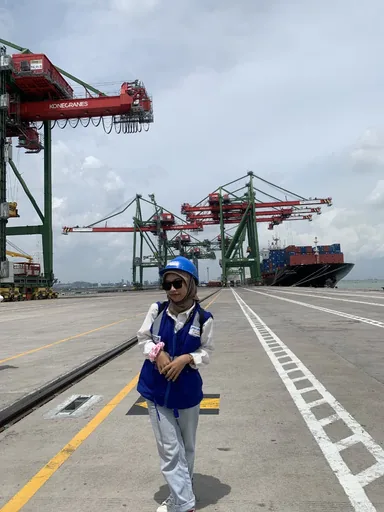 Alika in a Pelindo vest and helmet on the container terminal
